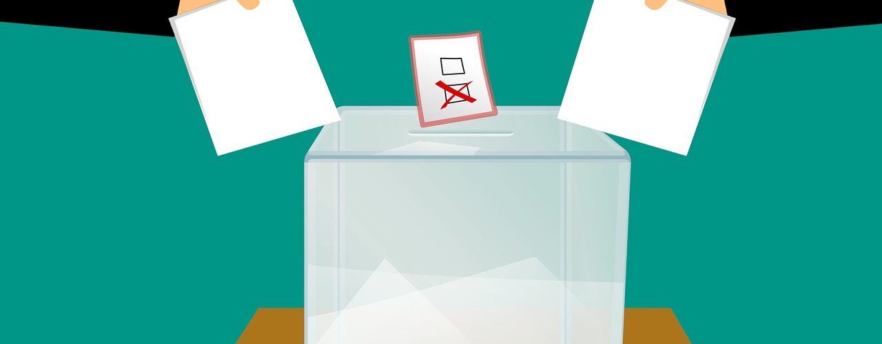Two people casting their vote into a ballot box